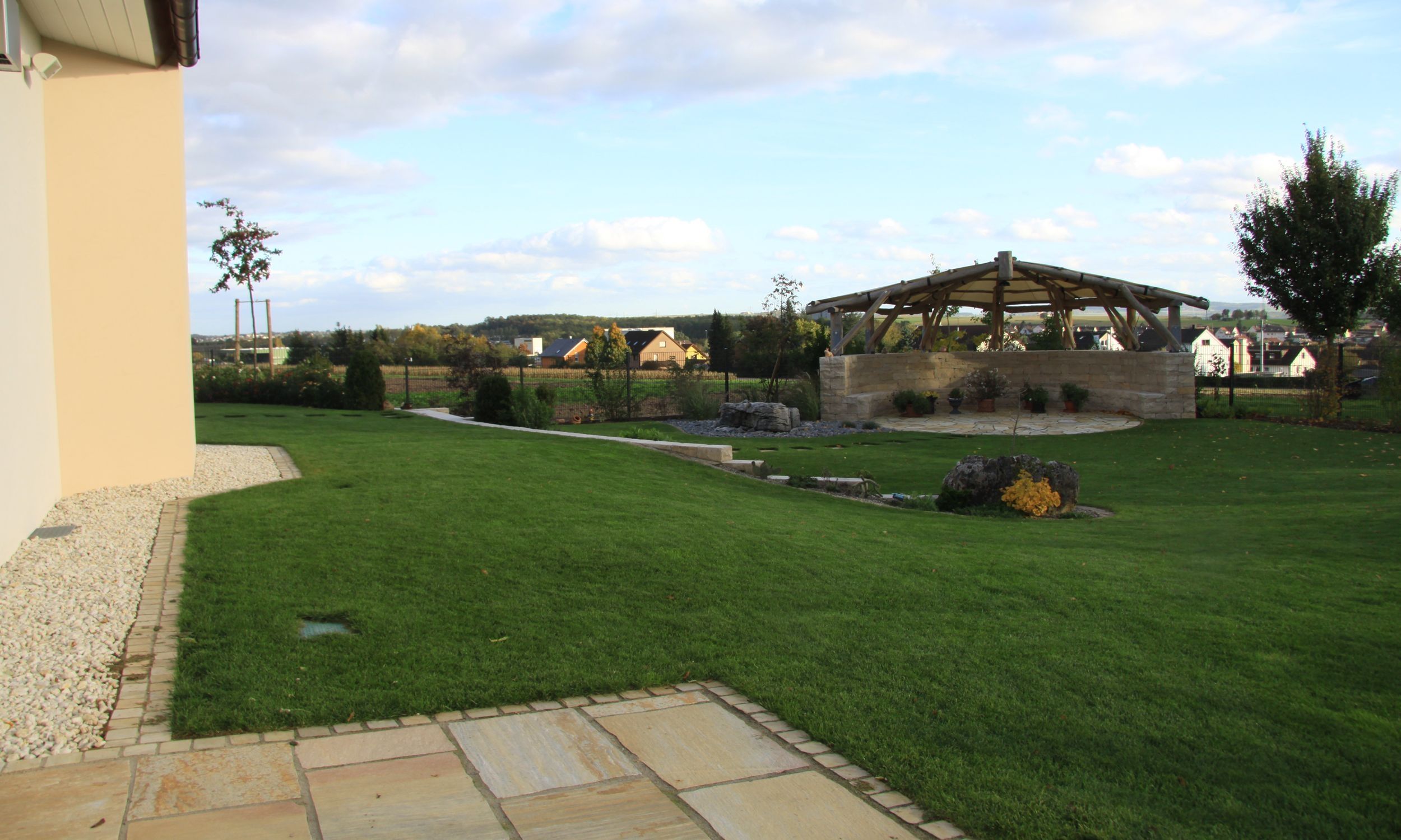 Ein grüner, gepflegter Rasen in einem sonnigen Garten, umgeben von Bäumen und Blumen